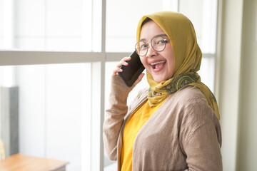 Business asian hijab woman smile wearing hijab and Orange T-shirt accept call phone