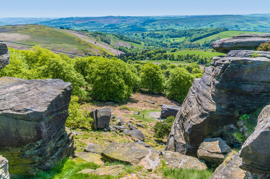 A view looking through a gap in the millstone rock caps of the Stanage Edge escarpment in the Peak District, UK in summertime