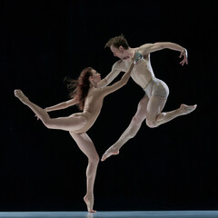 Freedom. Impressive young man and woman, talented, professional dancers performing ballet art against black studio background. Concept of beauty, classical dance style, inspiration, movements. Ad