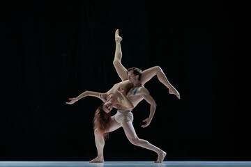 Graceful performance. Talented, artistic young woman and man, ballet dancers dancing against black...