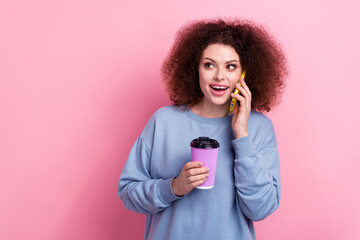 Photo of excited funky lady dressed blue pullover enjoying beverage talking phone looking empty space isolated pink color background