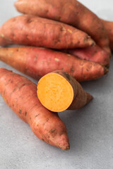 Raw sweet potatoes whole and cut. Orange kumara, sweet potato. Harvesting of root crops.  - obrazy, fototapety, plakaty