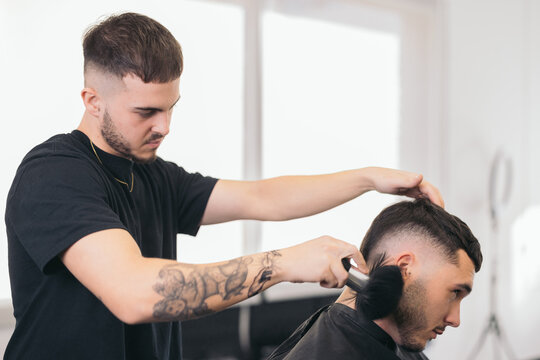 Young barber finishing haircut in hair salon