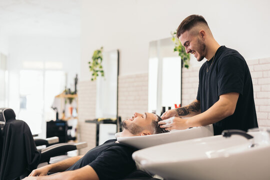 Young barber washing hair in barber shop