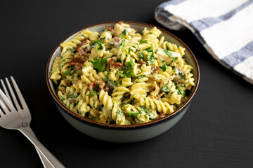 Homemade Chicken Spinach Alfredo Rotini Pasta in a Bowl on a black background, side view.