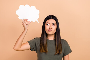 Photo of minded filipino lady look arm hold empty space cloud shape bubble card isolated on beige...