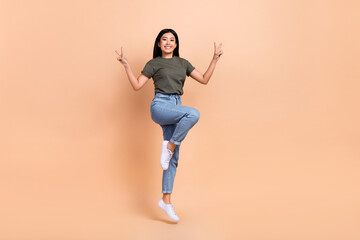 Fototapeta na wymiar Full body cadre of carefree chinese girl funky show double v-sign hello greetings advert outlet clothes isolated on beige color background