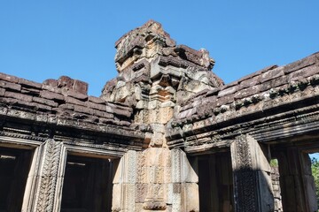 Ruins of ancient Khmer stone buildings against a clear blue sky.