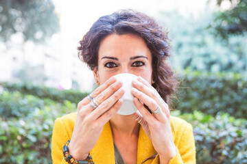 Close-up of woman looking at camera drinking from a cup of coffee