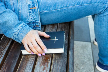 woman holding her hand on the bible lying on the bench.