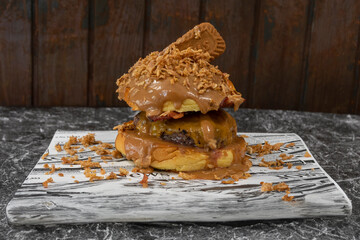 Detalle de una hamburguesa con carne, crema de cacahuetes, y galletas lotus