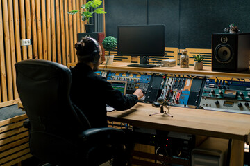 young sound engineer with headphones working in a music studio with monitors and an equalizer...