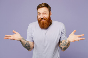 Young redhead bearded man he wear violet t-shirt casual clothes shrugging shoulders looking...