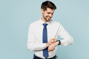 Young smiling cheerful fun employee IT business man corporate lawyer wear classic formal shirt tie smart watch check time work in office isolated on plain pastel light blue background studio portrait.