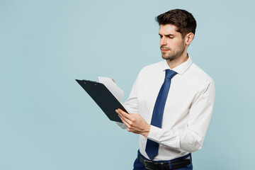 Obraz na płótnie Canvas Side view young employee IT business man corporate lawyer wears classic formal shirt tie work in office hold clipboard with paper account documents isolated on plain blue background studio portrait.