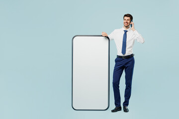 Full body fun young employee IT business man corporate lawyer wear classic shirt tie work in office big huge blank screen mobile cell phone smartphone with area talk isolated on plain blue background.