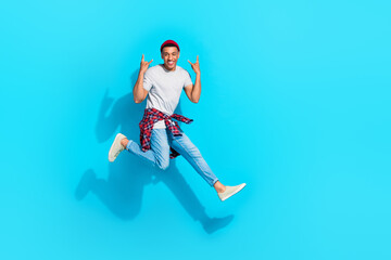 Fototapeta na wymiar Full length portrait of active excited person jumping hands fingers demonstrate heavy metal symbol empty space isolated on blue color background