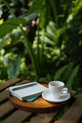 White coffee cup on wooden table with notebooks on wooden tray