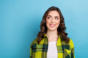 Fototapeta premium Photo of optimistic satisfied dreamy woman curly hairdo dressed checkered shirt look empty space sale isolated on blue color background