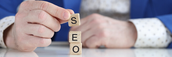 Businessman collecting words seo with wooden cubes