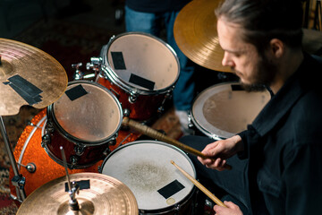 Obraz premium a young male drummer plays a drum kit in a recording studio at a professional musician's rehearsal recording a song