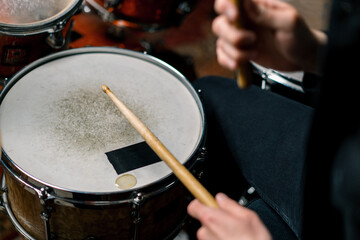 Fototapeta na wymiar drummer plays a drum kit in a recording studio at a professional musician rehearsal recording a song beats the sticks on the instrument close-up