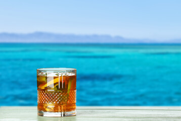 Glass of tasty cold ice tea on table at sea resort