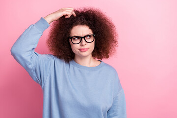 Photo of doubtful unsure girl wear blue shirt spectacles finger head looking empty space isolated pink color background