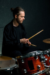 a young male drummer plays a drum kit in a recording studio at a professional musician's rehearsal recording a song