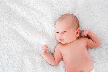 Little newborn baby boy lying on white bed