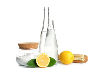 Bottles of vinegar, baking soda, brush and lemons on white background