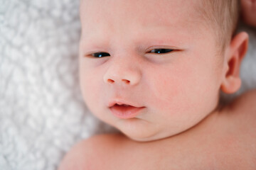 Little newborn baby boy lying on white bed closeup