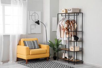 Interior of light room with shelving unit and clothes
