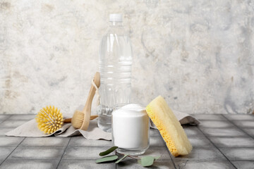 Glass of baking soda, vinegar and cleaning supplies on table