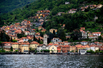 Fototapeta na wymiar Landscape view of one of the many small towns on Lake Como with a church in the foreground and houses on a hillside during the rain in northern Italy