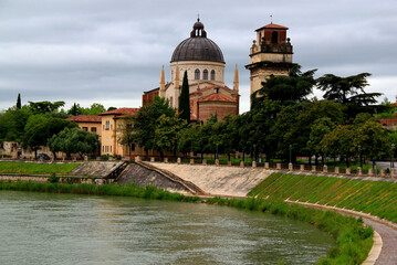 Fototapeta na wymiar Photo showing the church of San Giorgio in Braida and the Adige river in the foreground against a stormy sky in the city of Verona, northern Italy