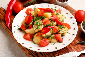 Plate of tasty Potato Salad with vegetables on light background