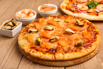 Board with tasty seafood pizza on wooden background