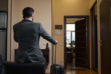 Hotel guest in business suit sat on back of sofa