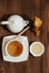 Liquid fresh linden honey in a plate with a wooden honey spoon and tea.