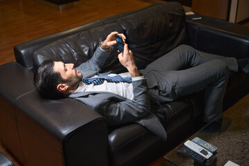 Fototapeta premium Man rests on a leather sofa in a hotel room