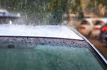 Heavy summer rain with hail. Strong streams of water fall on the roof of a sports car. The splashes...