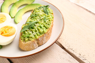 Plate of tasty bruschetta with avocado on light wooden background, closeup