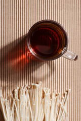 Natural medicine, reduce stress and improve immunity concept. Mushroom hot drink. Tea in glass mug with mushrooms on brown background. Copy space. 