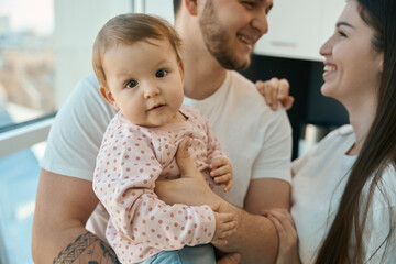 Charming little girl with plump cheeks in her fathers arms