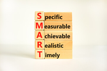 SMART symbol. Concept words SMART specific measurable achievable realistic timely on wooden block. Beautiful white background. Business SMART specific measurable achievable realistic timely concept.