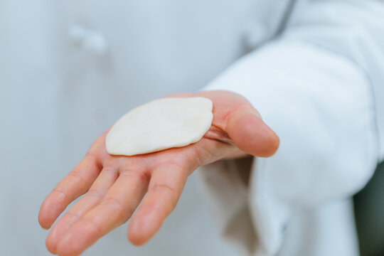 A chef's open hand holding Chinese bao dumplings dough, closeup
