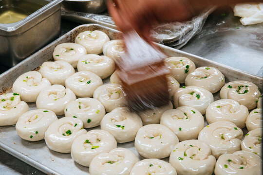 scallion pancakes on a tray being brushed with liquid, motion blur