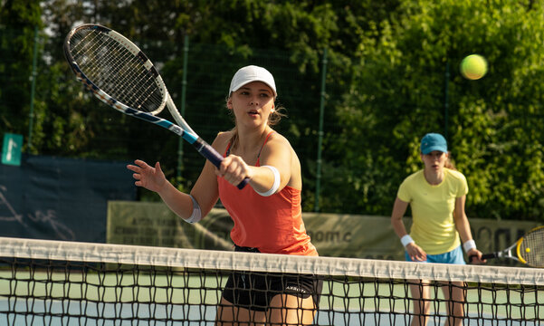 Two competitive female tennis players engage in an intense match, their swift movements and powerful strokes showcasing their dedication and love for the sport. - Powered by Adobe