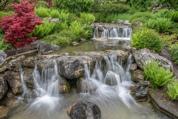 beautiful landscape with waterfall falling from stone wall in japanese style landscape park. Selective focus.